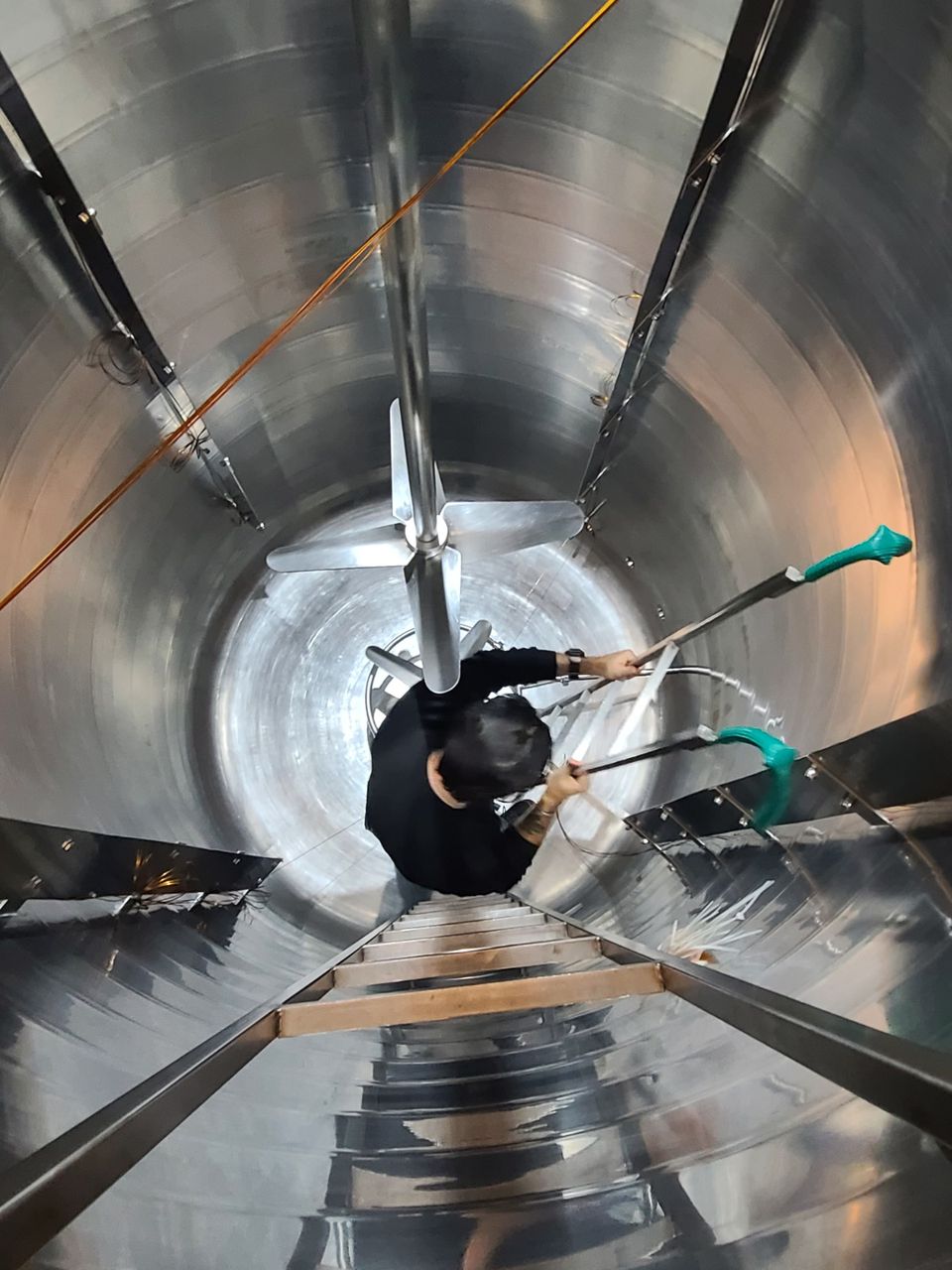 Profesional descendiendo por la escalera interna de un reactor de acero inoxidable durante un mapeo térmico